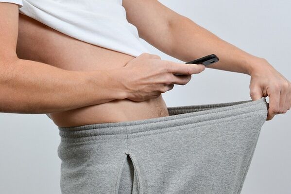 un bărbat se uită în jos la pantaloni la un penis mărit